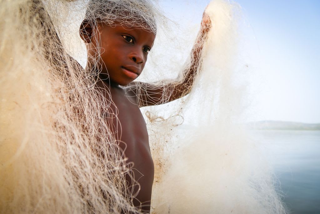 A young boy draped in fishing line.