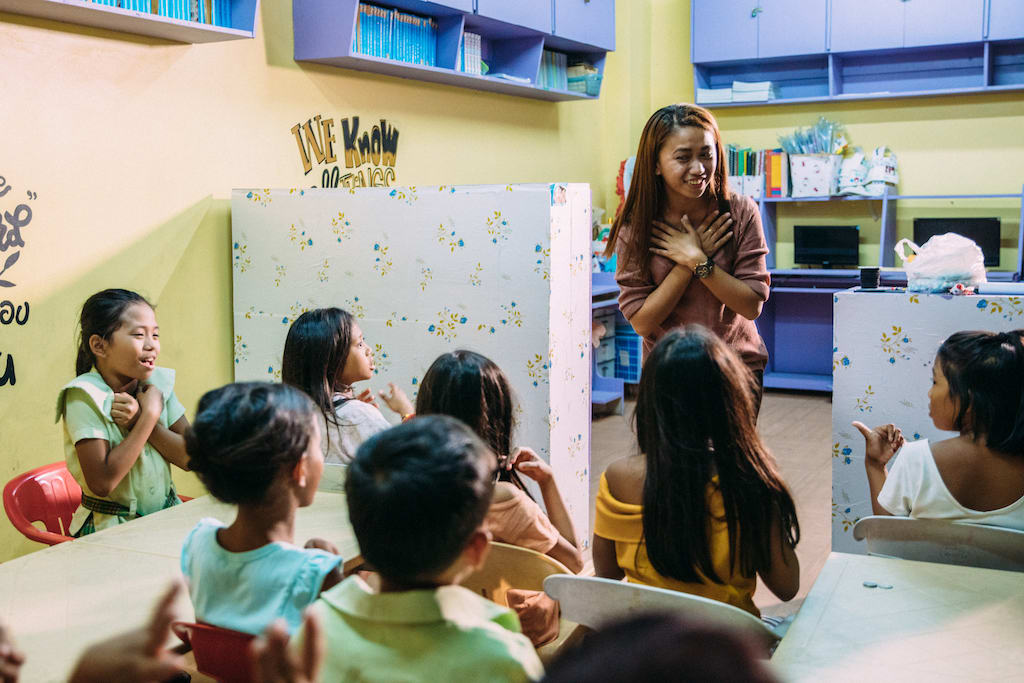 A young woman teaching a class of young children.