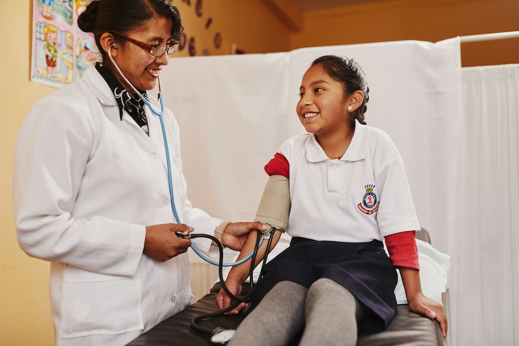 A doctor examines a child, taking her blood pressure.