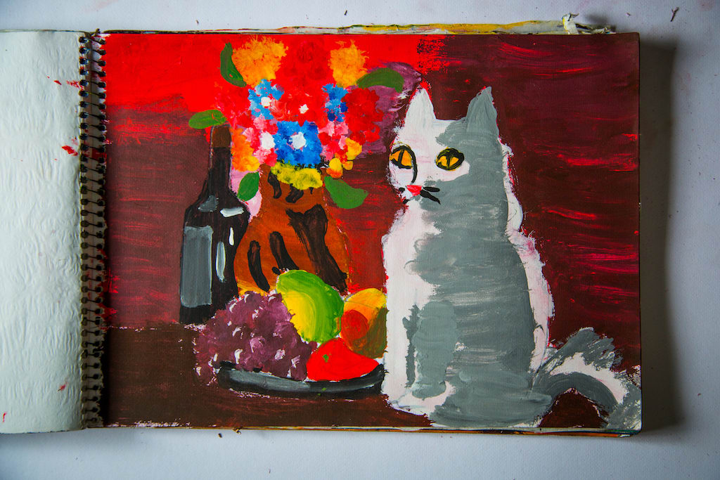 One of Hector's paintings, of a white cat sitting next of a vase of flowers.