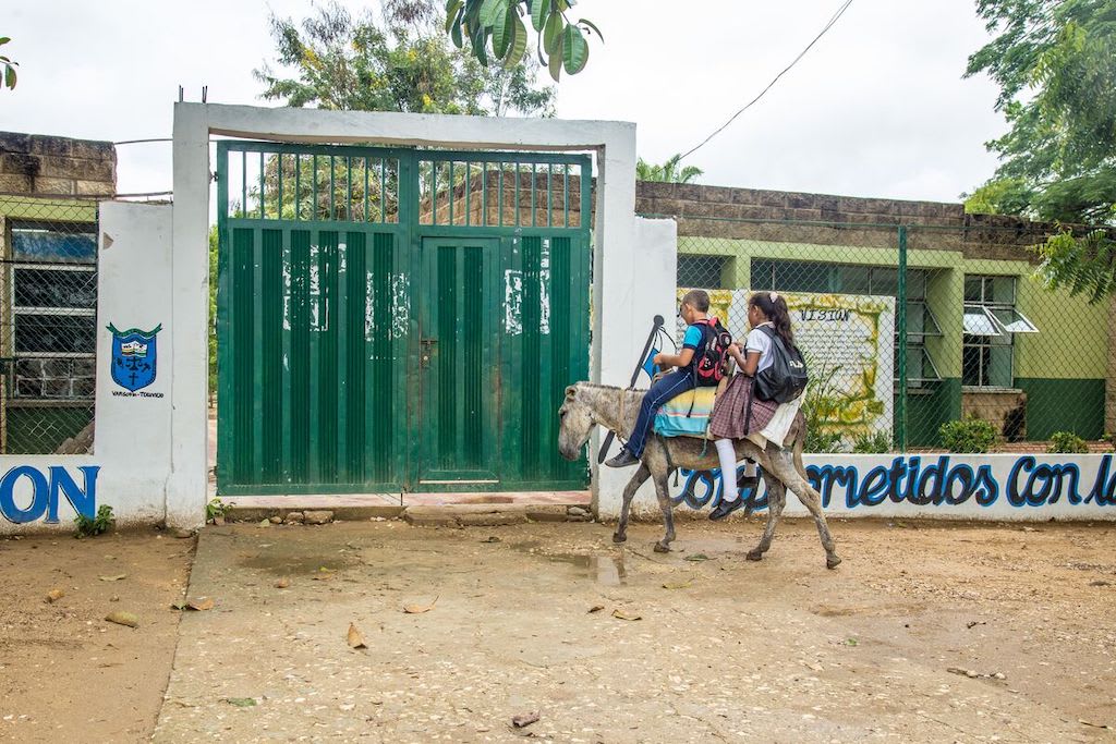 The donkey carrying Dilan and Dianis arrives at the school gate.
