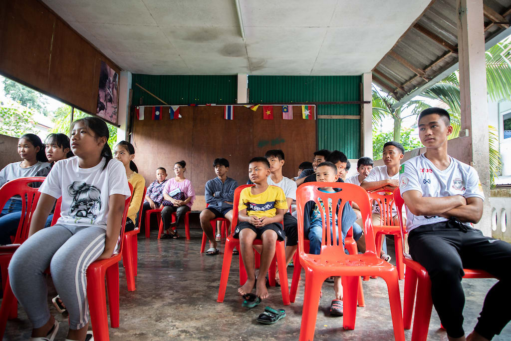 Thai children sit in red chairs in a classroom at the Compassion centre.