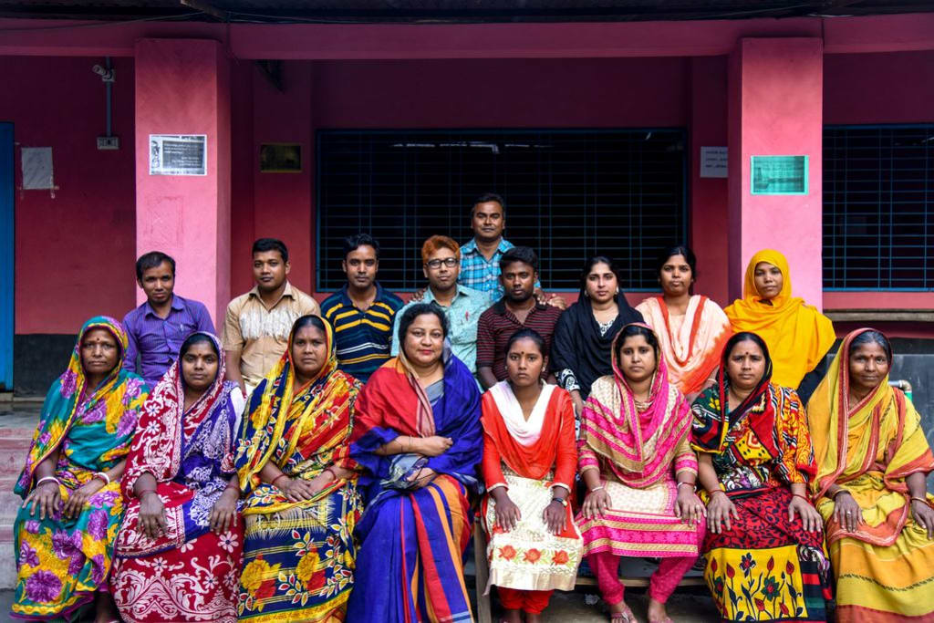 The staff at Ratna’s child development centre sit together in a group in front of the centre.