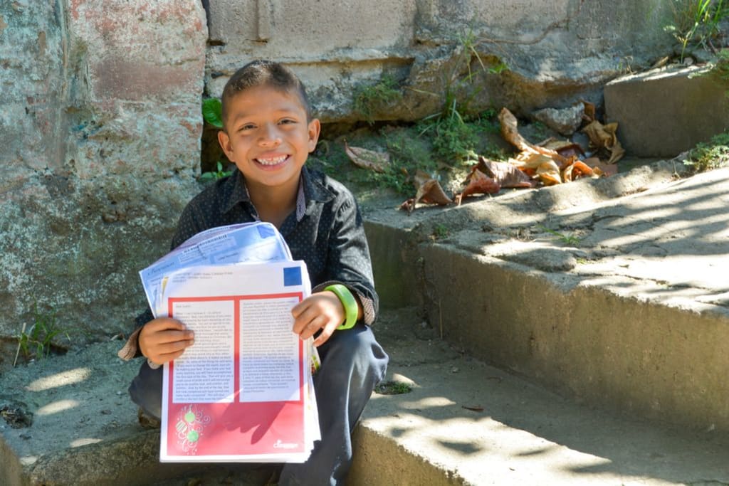 Justin, in El Salvador, proudly shows off a stack of letters from his sponsor.