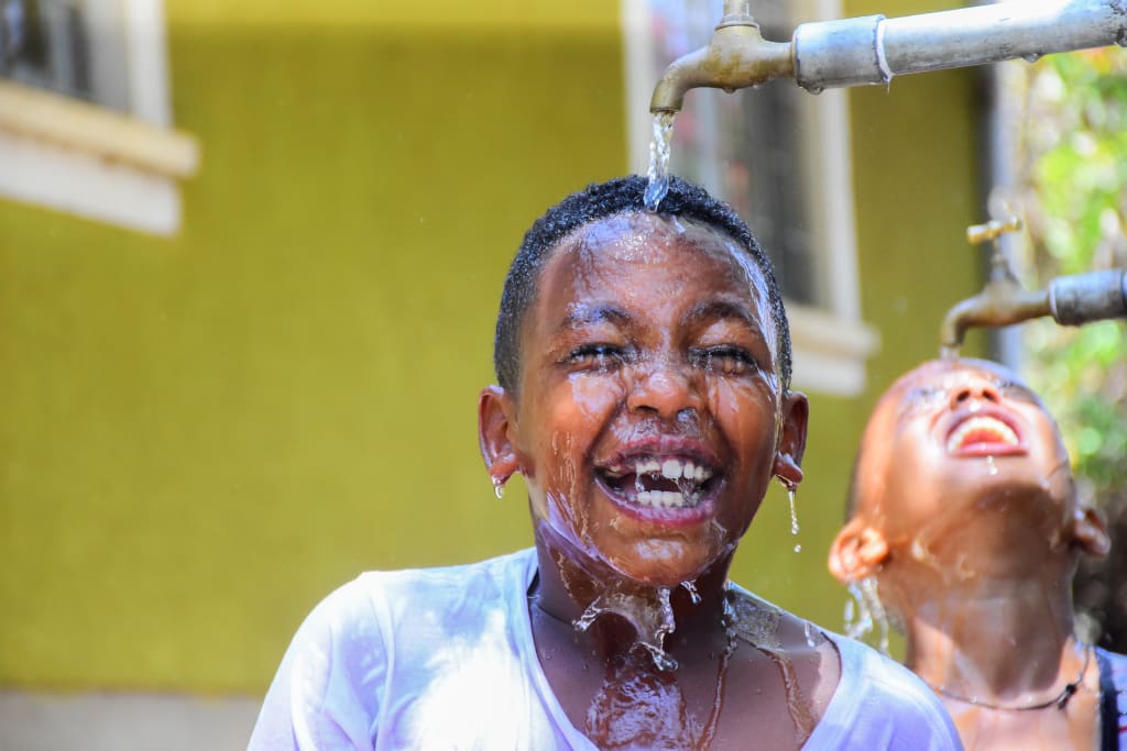 little boy laughs under a clean water spout