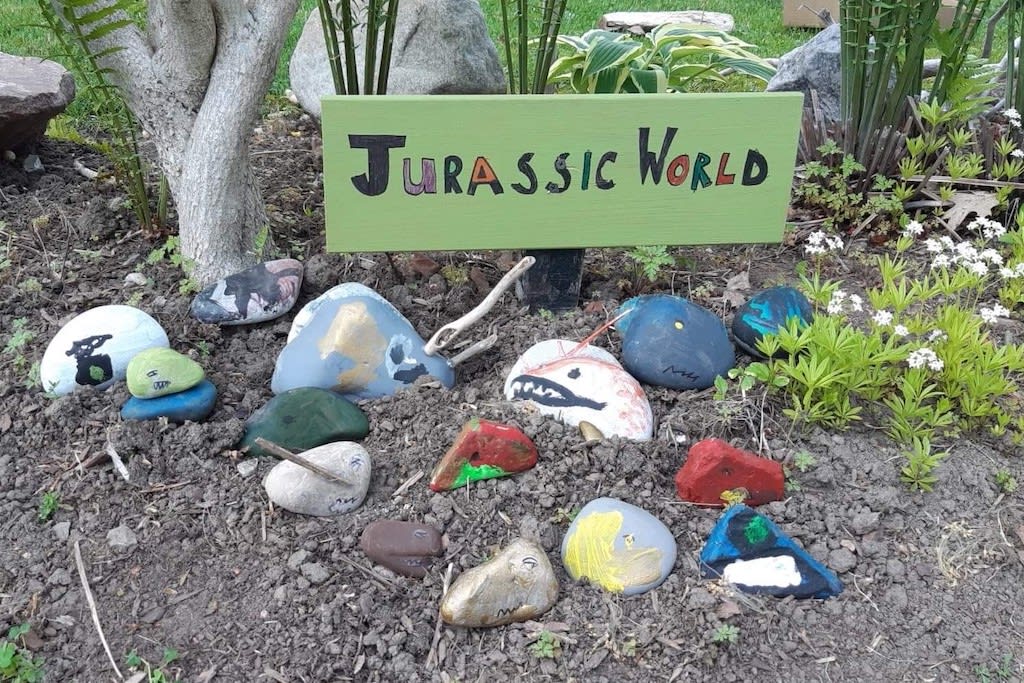 Painted rocks outside under a sign that reads 'Jurassic World'.