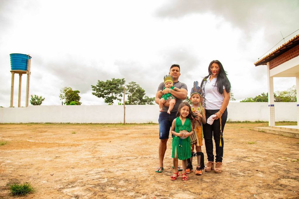 Cacique Magno is standing outside with his wife Michelly, and his children Kaio, Kaila, and Mayara during an indigenous festival.