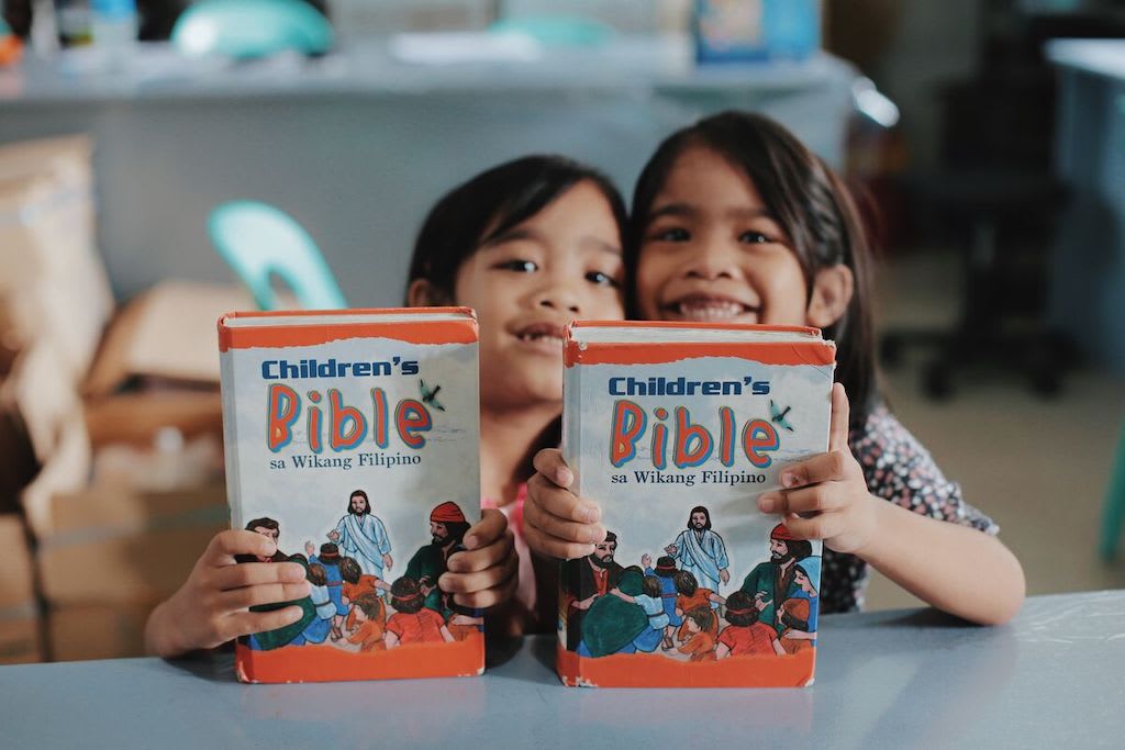 Two girls holding children's Bibles.