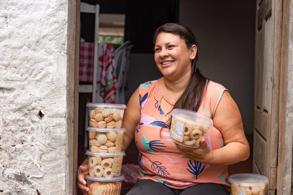 A woman from Brazil sits with cookies made in the income generation initiative.