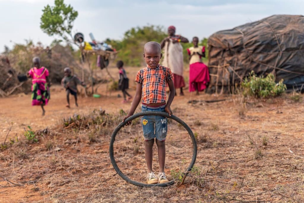 A boy stands holding a wheel and looks at the camera