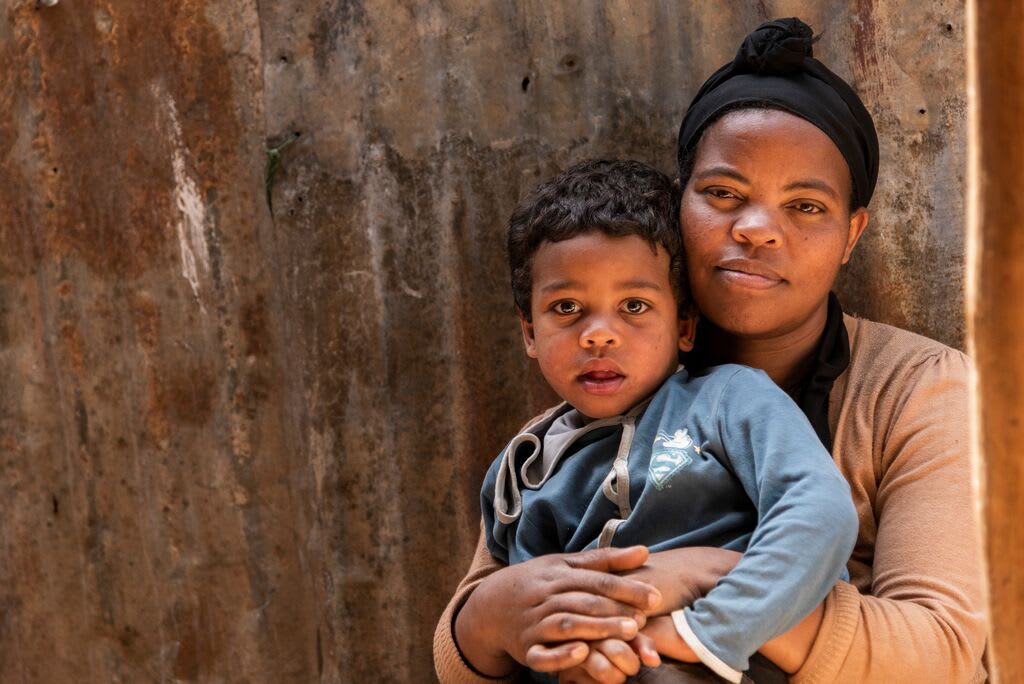 Abiyot and her young son pose together in front of their home