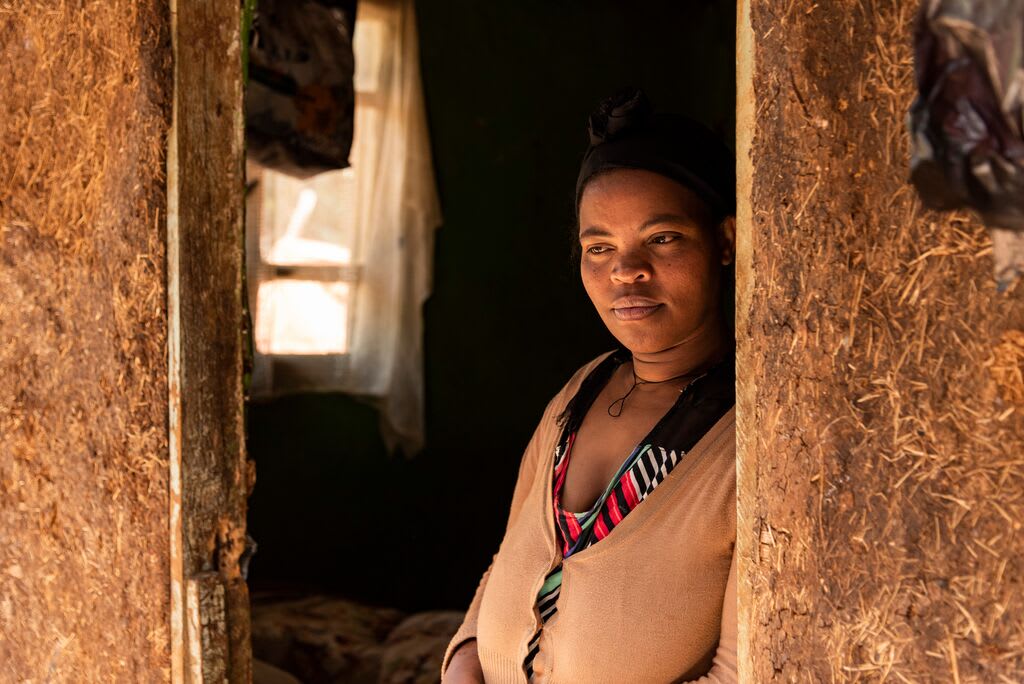 Abiyot stands in her doorway with a hopeful look on her face.