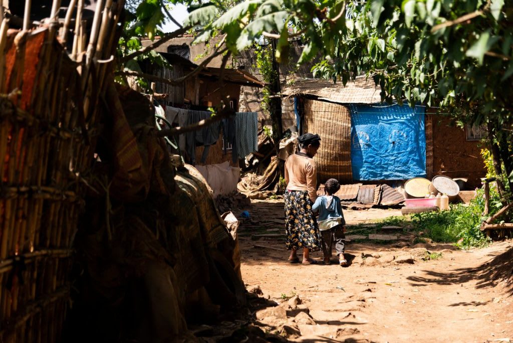 Abiyot and her young son walk together hand in hand in their village.