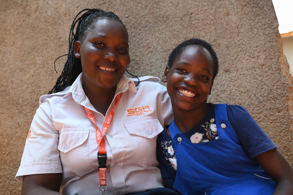 Juliet smiles with her mother, Agnes, who is wearing her security guard uniform.
