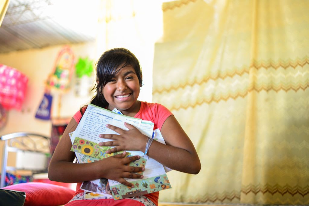 Maria sits in her home in Peru, clutching an armful of beloved letters from her sponsor.
