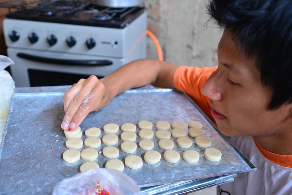 A teen boy making pastries.