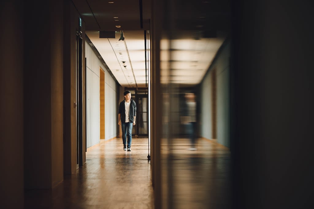 A young man walks down a hallway.