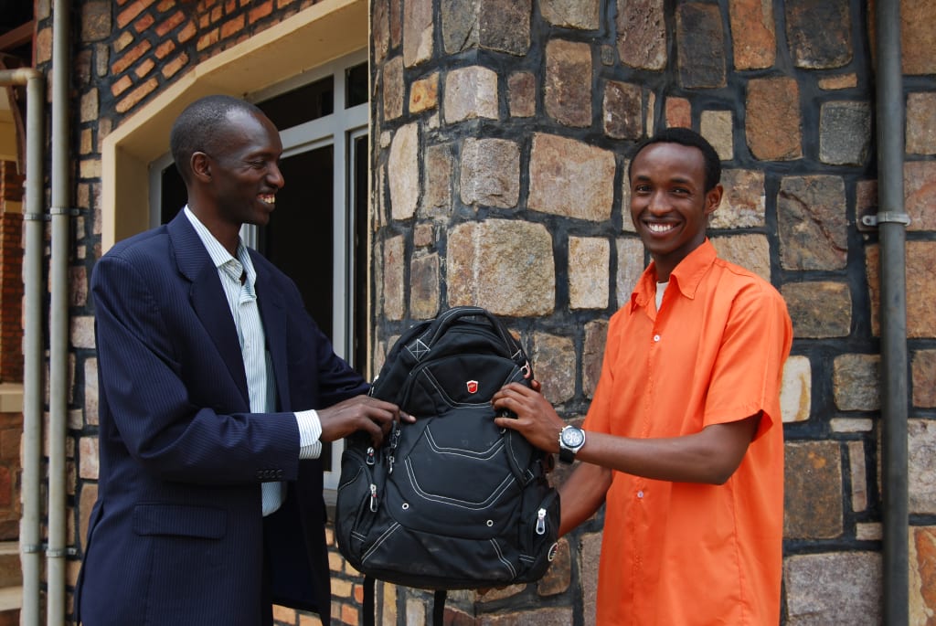 A man in a suit gives a young man a black new backpack as a gift at Christmas