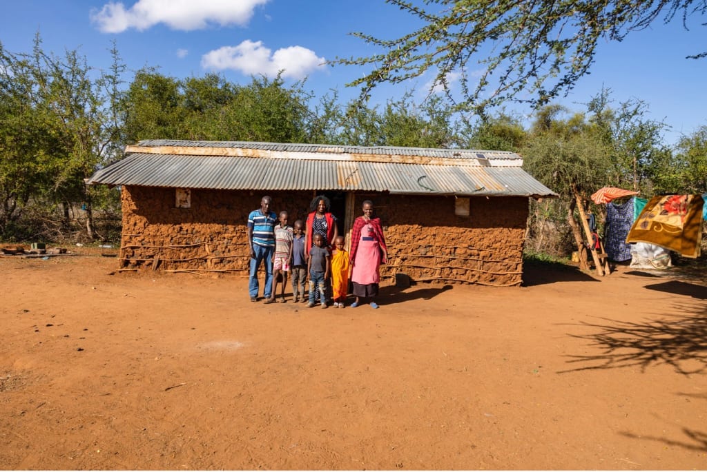 Janet stands outside of her home with her family of 7.