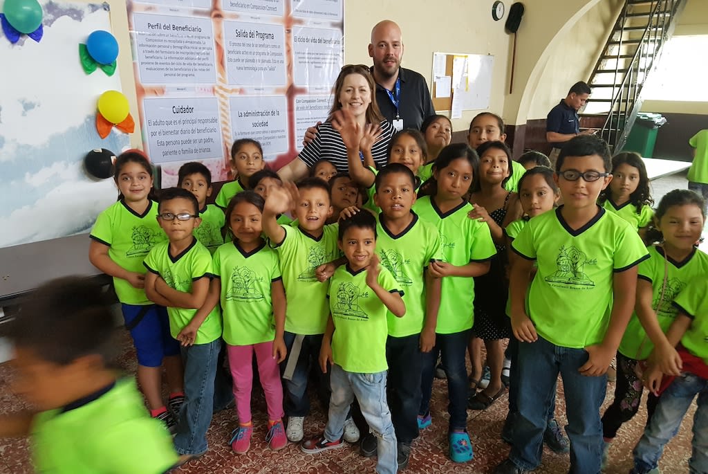 Jeff and Kim with a group of Compassion children all wearing green uniforms.