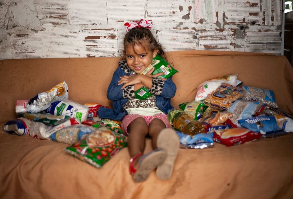 Little girl on her couch surrounded in packaged foods, smiling