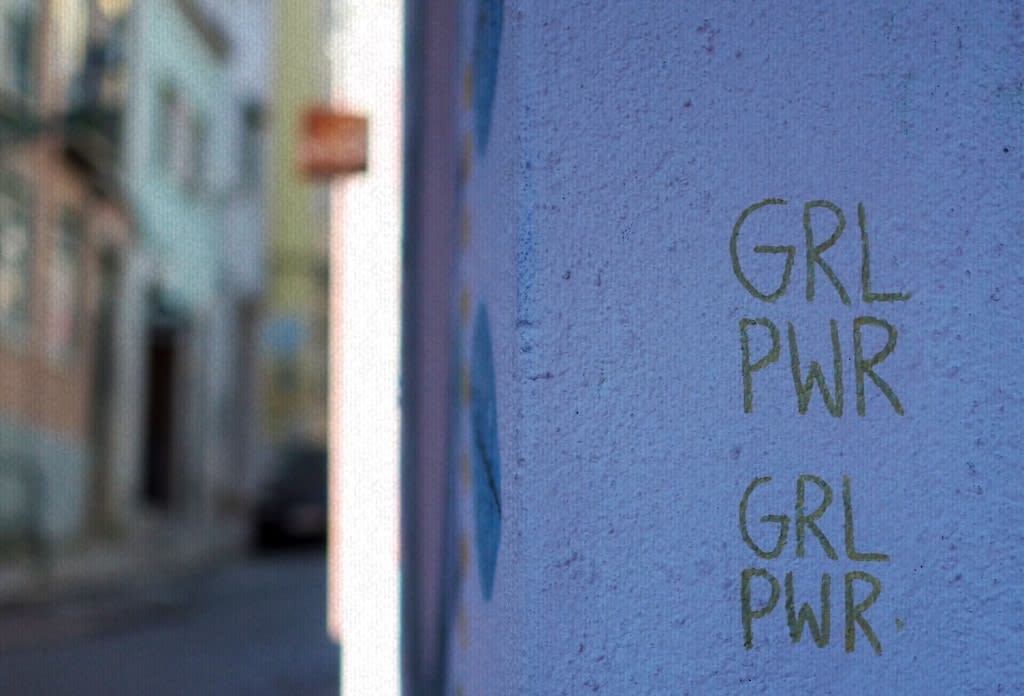 A wall with "GRL PWR" written on it.