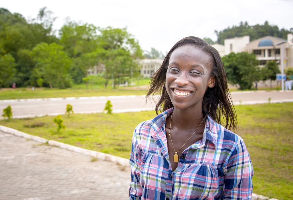 A portrait of Georgina, smiling on her university campus.