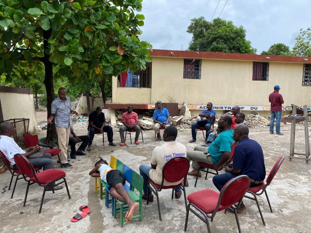 A group sits in a circle under a tree