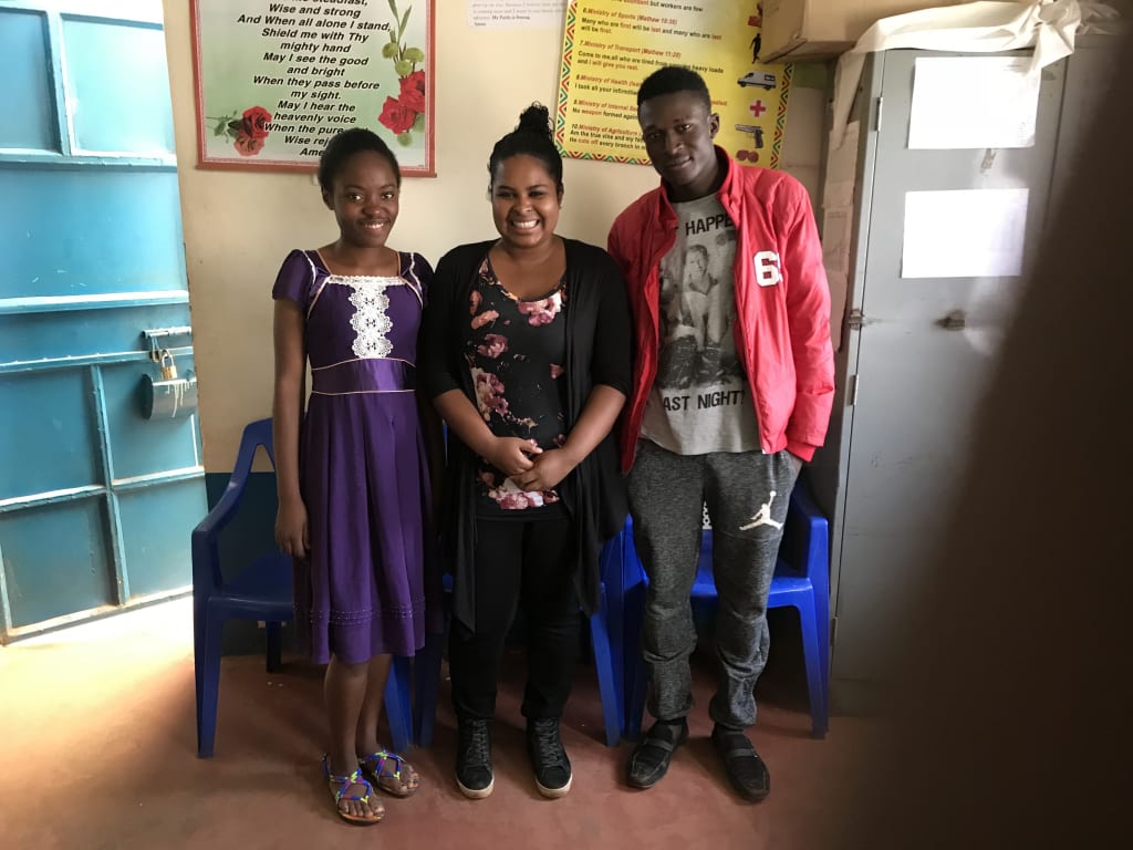 Sarah poses with both of her sponsor children in a classroom.