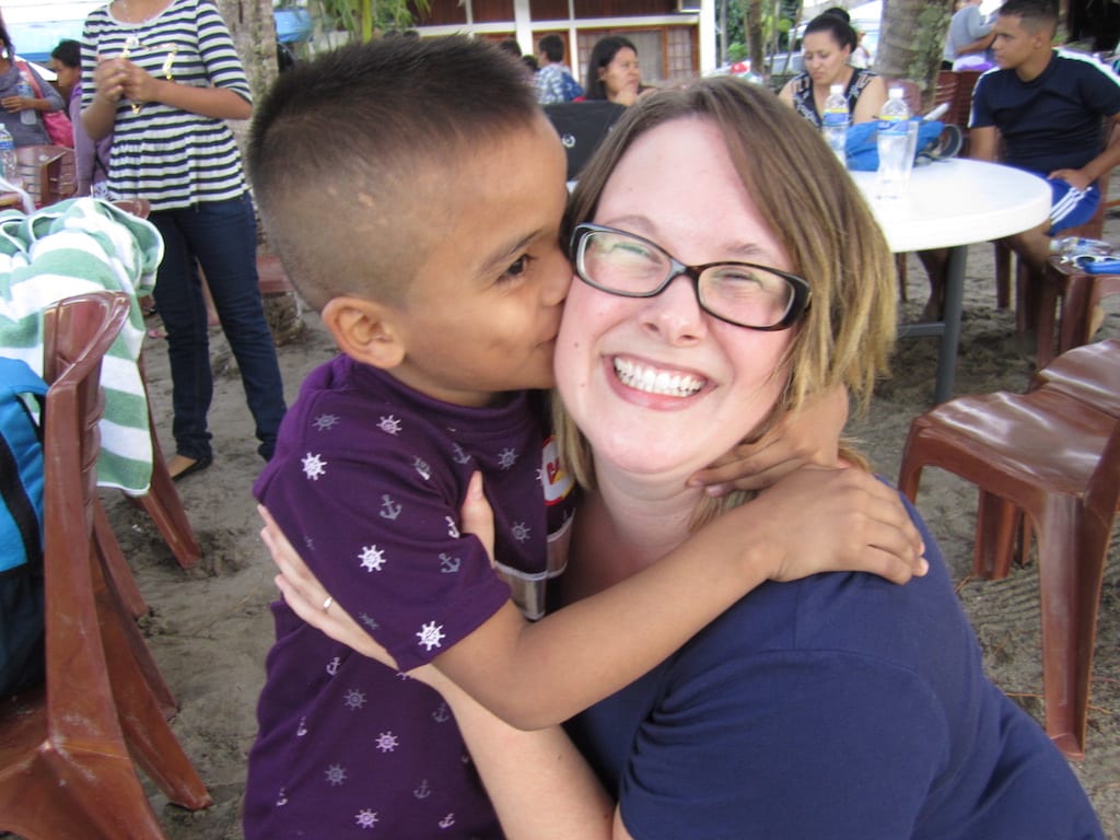 A young boy gives a woman a kiss on the cheek.