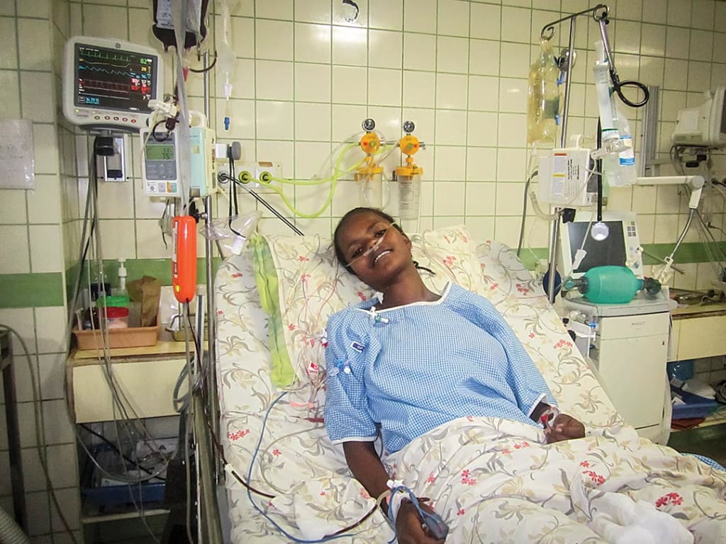 A teenage girl sits in hospital bed. Recovering from surgery.
