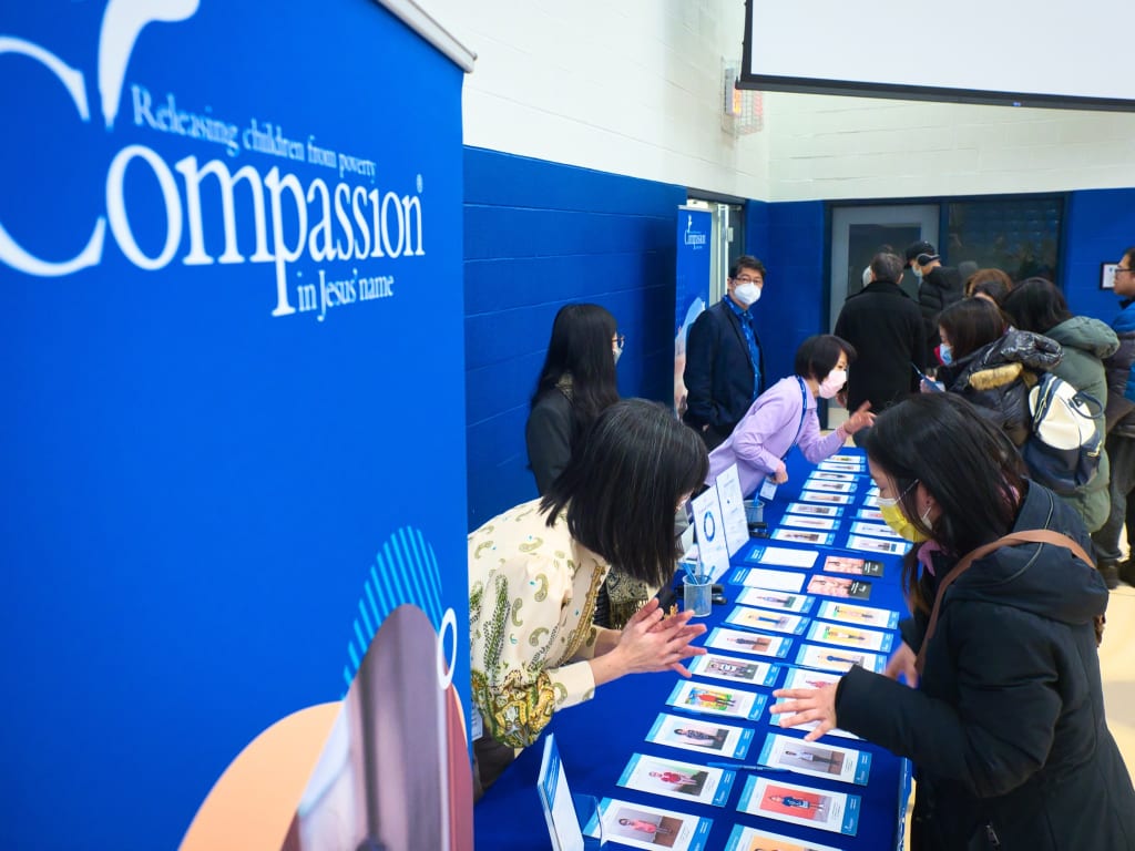 Compassion staff and volunteers speaking with prospective sponsors at a Compassion church event.