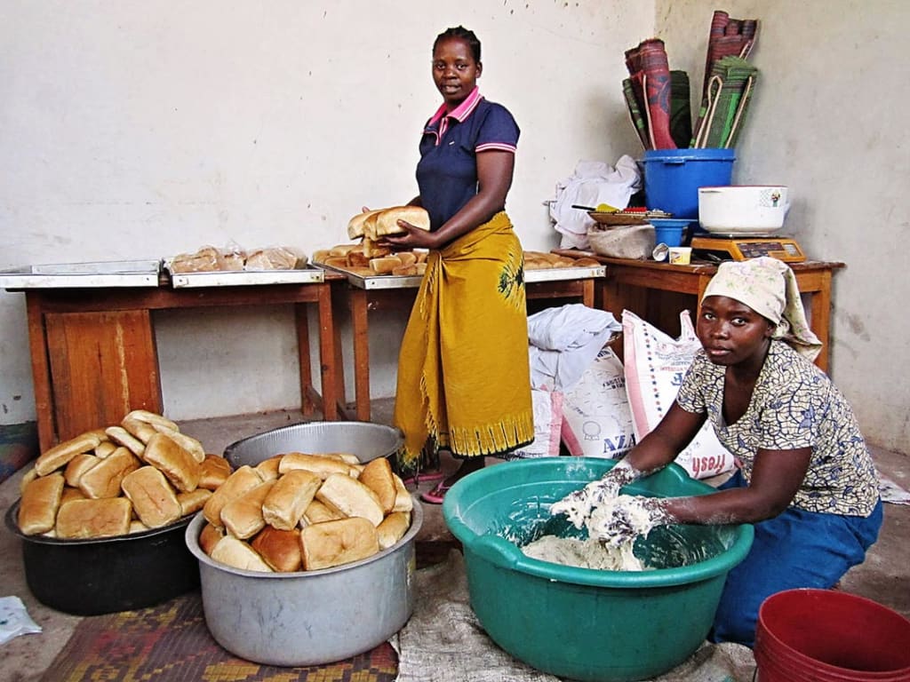 Two moms baking bread in a bakery in Tanzania.