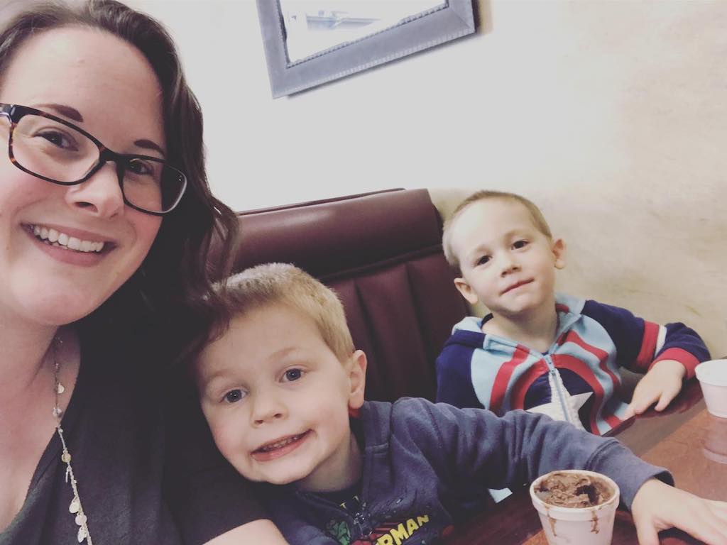 A selfie of a mom with her two sons in a restaurant booth.