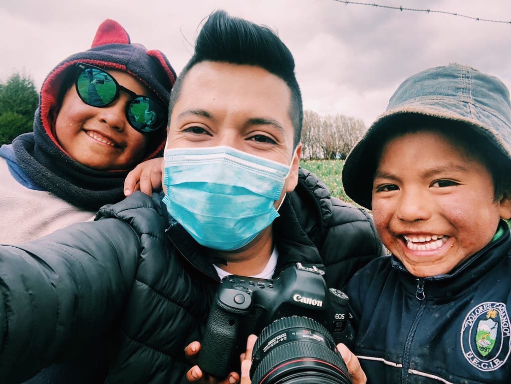 Nico takes a selfie with his mask with two kids smiling beside him.