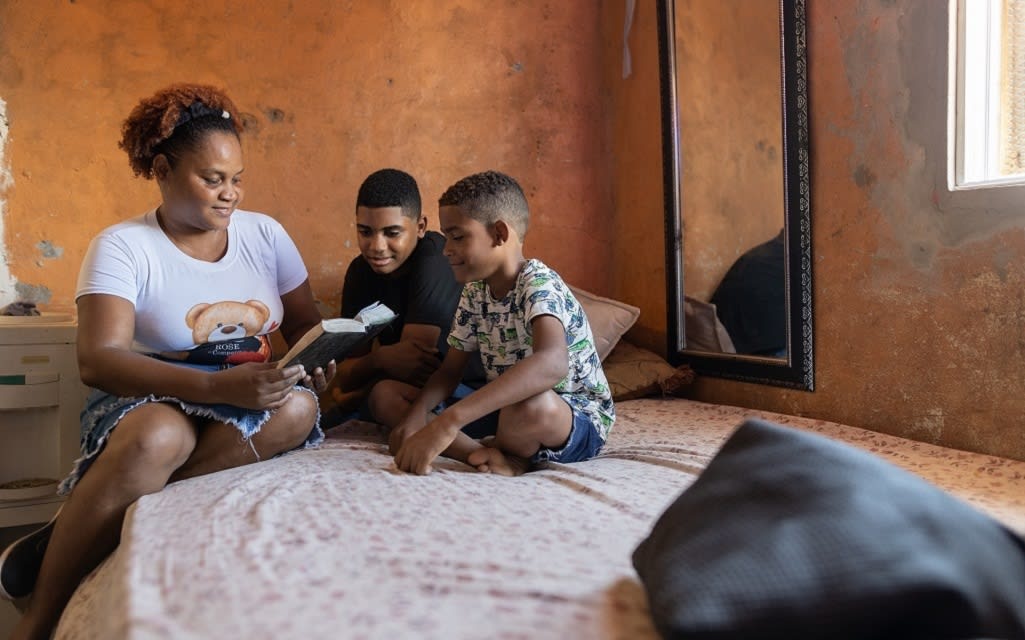 Yenny and her two boys, Geremy and Jeremias, read the Bible on the mattress she made.