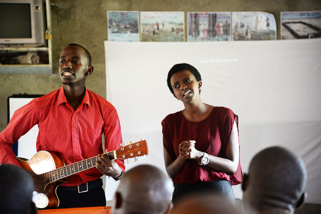 Bienvenue plays guitar and sings to a crowd.