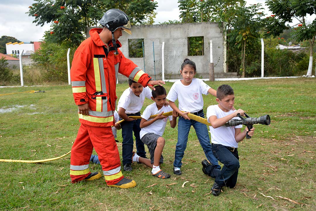 Jonathan, a Compassion graduate and firefighter, shows compassion children how to use a fire hose.