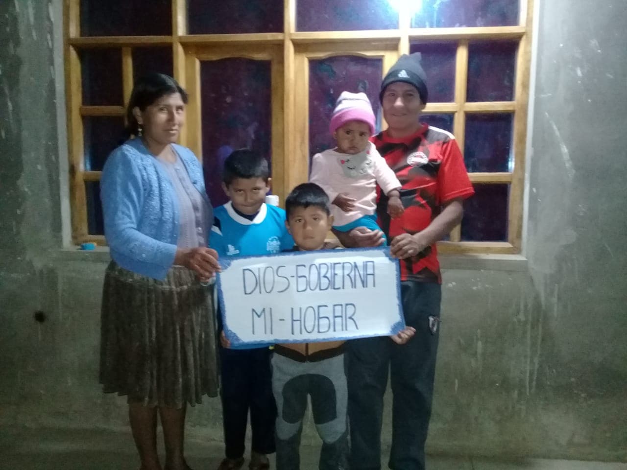A family stands together holding a sign.