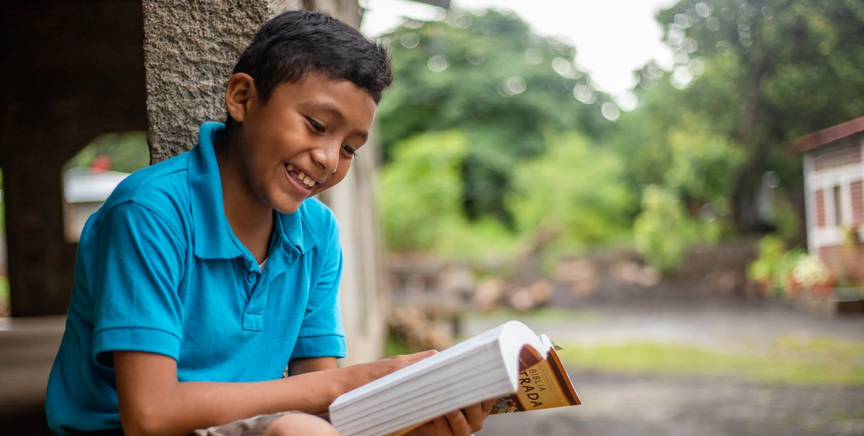 A boy reading a book with a big smile on his face