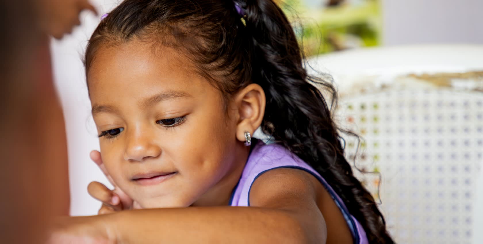 A little girl looking down at her desk