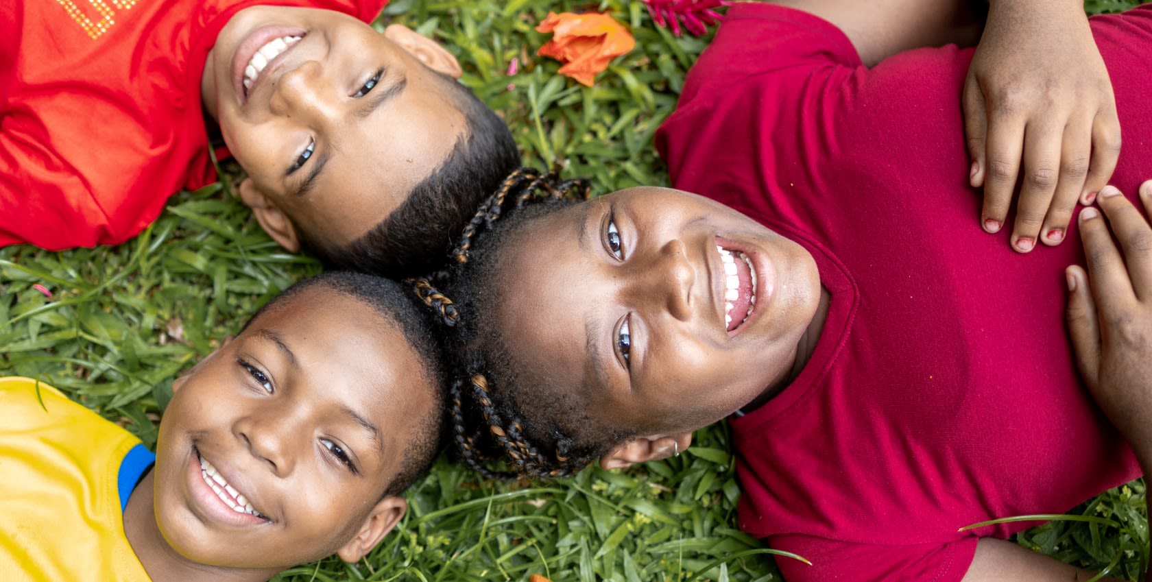 3 boys lying on the ground smiling to the camera.