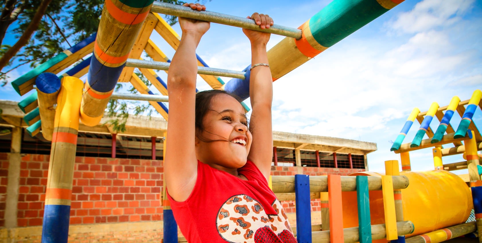 A girl playing at a playground, smiling happily.