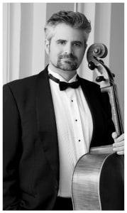 Black and white photo of a man in a suit with a cello
