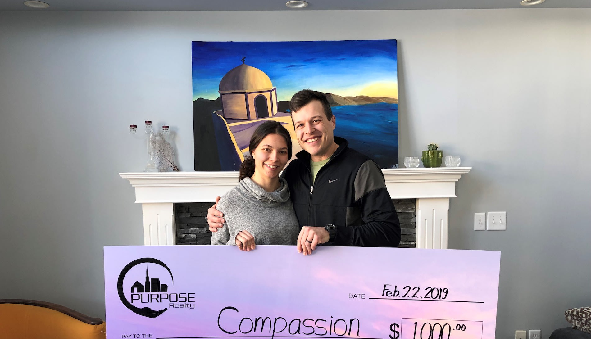 Man and woman smile, holding a cheque for Compassion.