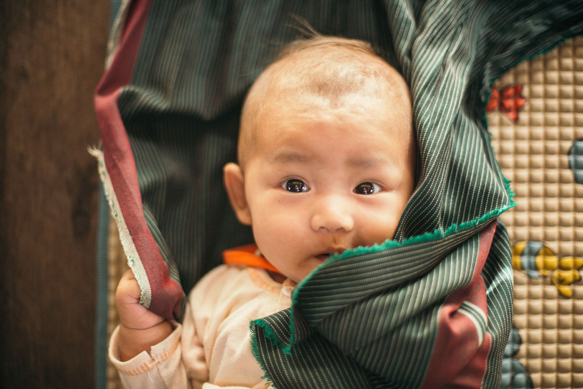 A close up of baby wrapped in a green and red blanket.