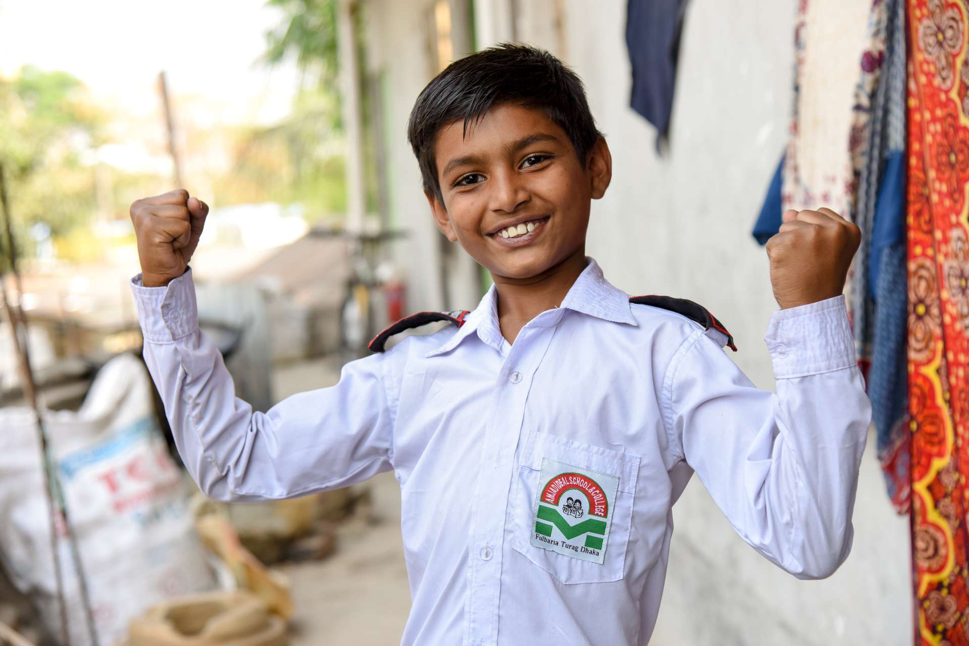 Boy flexes his muscles and shows off his uniform shirt.
