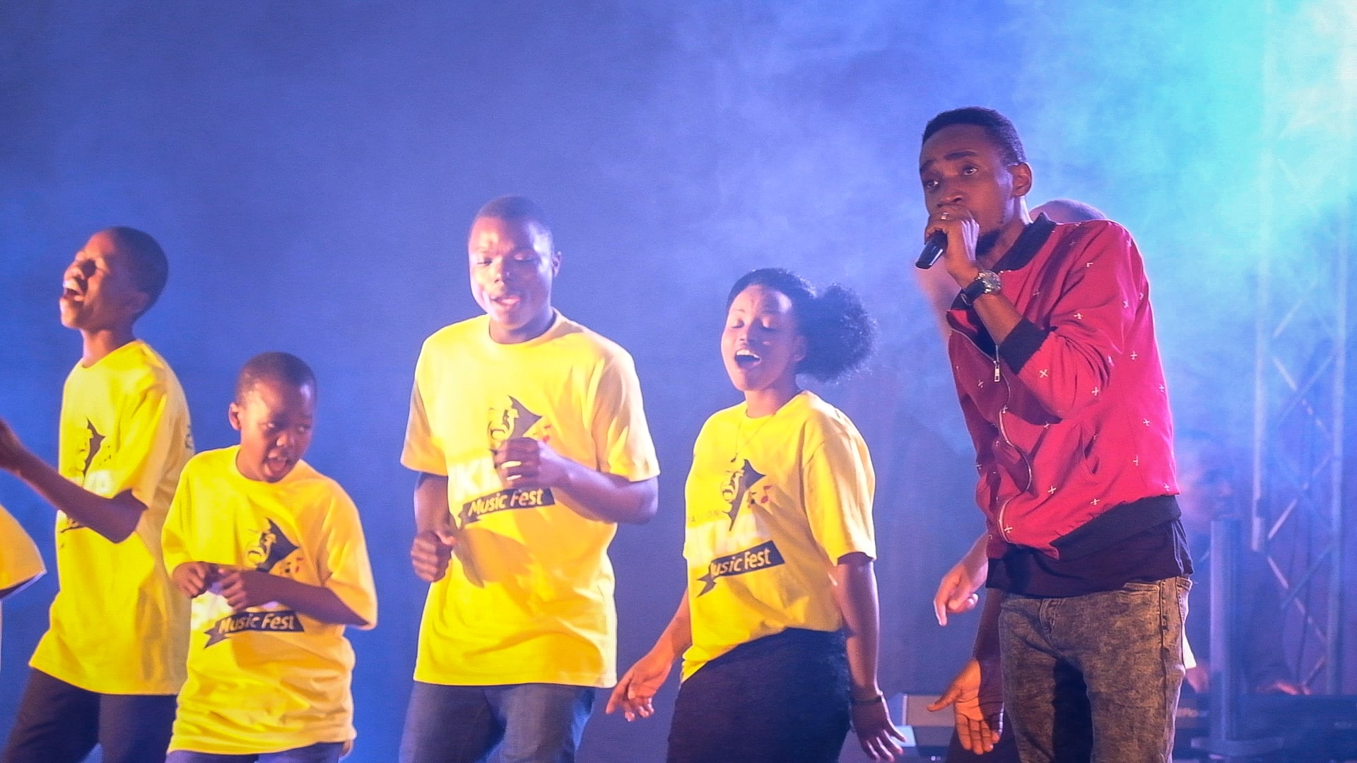A group of Tanzanian teens sing on stage.