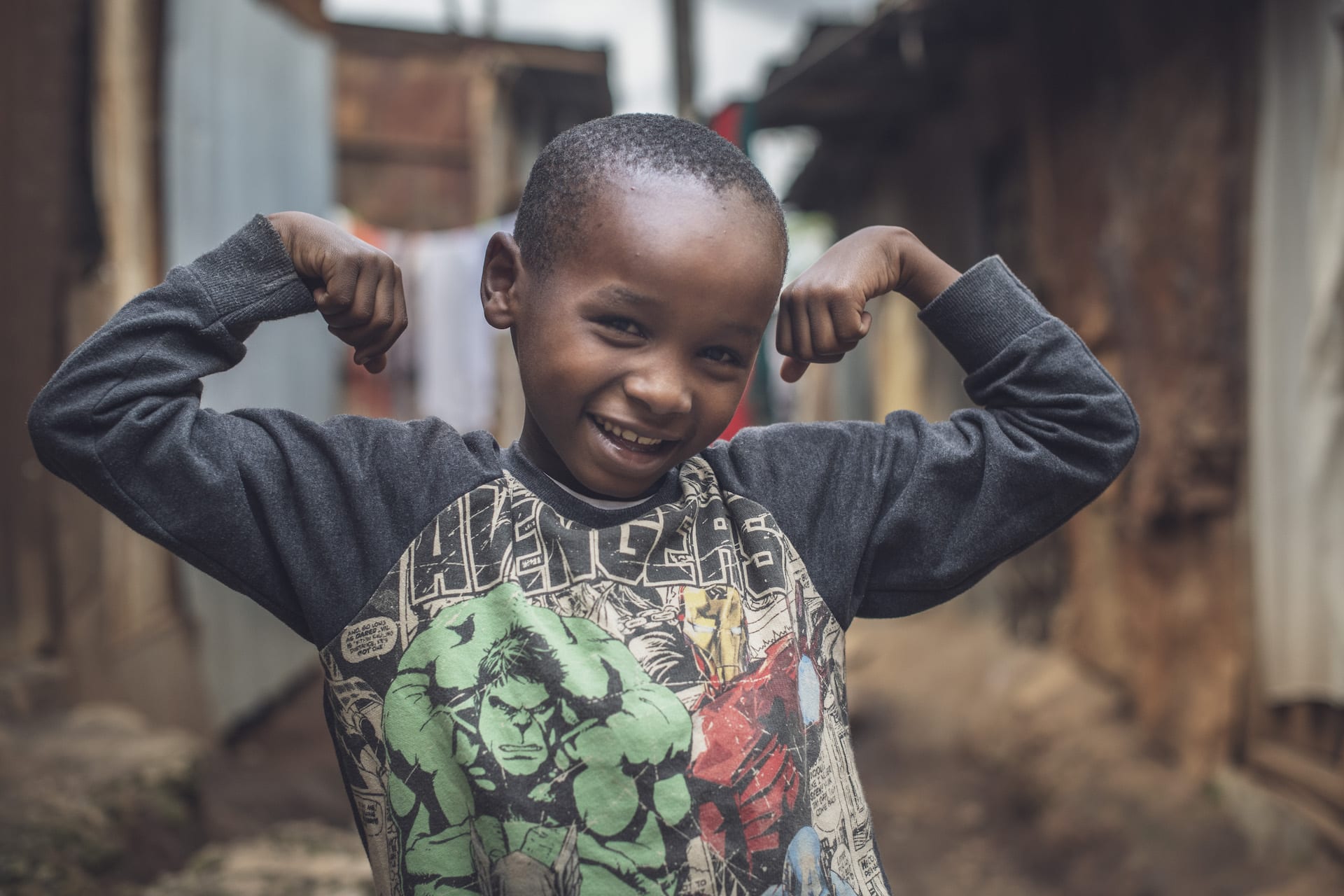 A boy stands flexing his arms.
