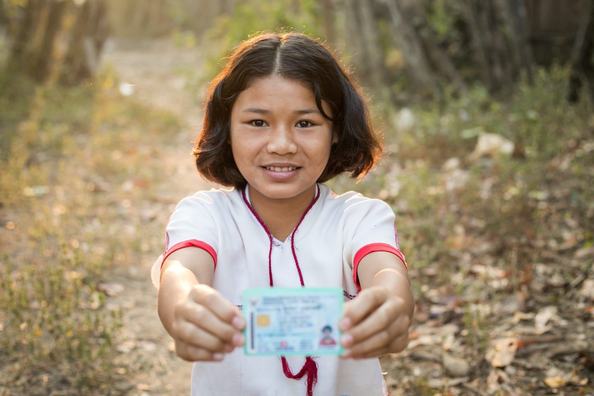 Young girl smiles and holds her citizenship card.